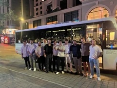 A group of passengers outside a luxury ALR party bus during an evening celebration.